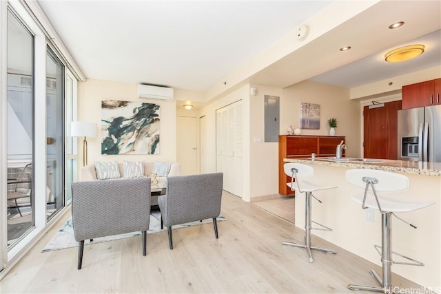 dining space with a wall mounted air conditioner, light hardwood / wood-style floors, sink, and electric panel