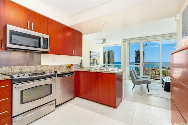 kitchen with sink, ceiling fan, stainless steel appliances, light stone counters, and kitchen peninsula