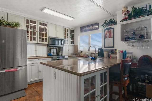 kitchen featuring sink, stainless steel appliances, a breakfast bar area, white cabinets, and dark tile patterned flooring