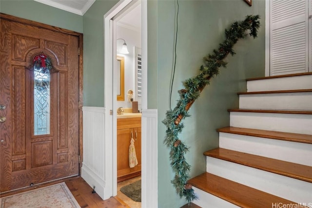 foyer entrance with ornamental molding, sink, and light hardwood / wood-style flooring