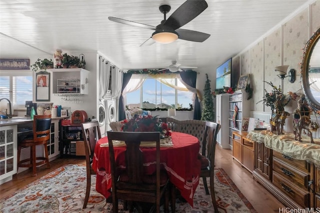 dining room with ceiling fan, washer and clothes dryer, ornamental molding, and hardwood / wood-style flooring