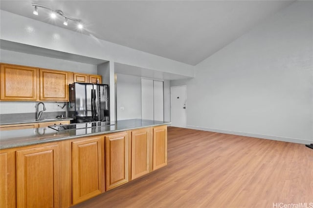 kitchen featuring sink, light hardwood / wood-style floors, lofted ceiling, and black appliances