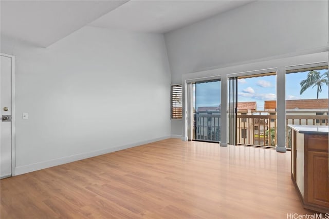 unfurnished room featuring light wood-type flooring and vaulted ceiling