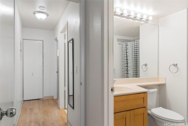 bathroom featuring hardwood / wood-style floors, vanity, toilet, and a textured ceiling