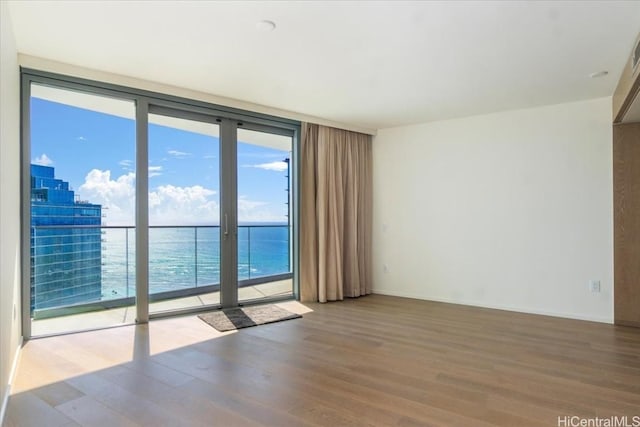 empty room featuring hardwood / wood-style floors, a water view, and floor to ceiling windows