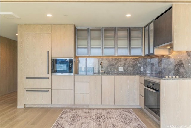 kitchen with light brown cabinets, light hardwood / wood-style floors, oven, and built in microwave