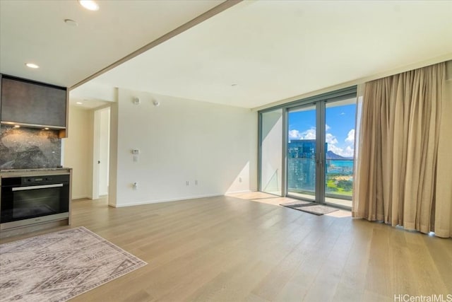 unfurnished living room featuring expansive windows and light hardwood / wood-style floors