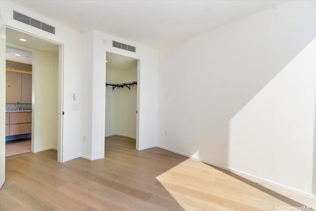 unfurnished bedroom featuring light hardwood / wood-style floors, a walk in closet, and a closet