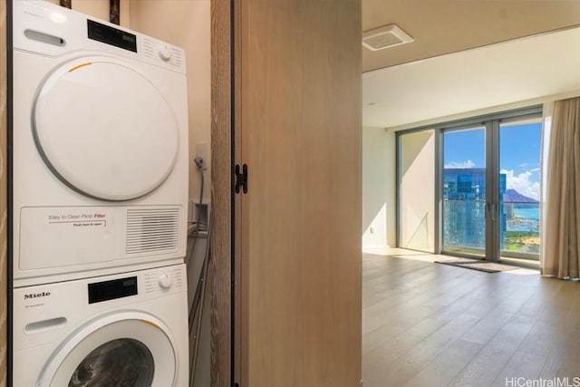 laundry room with stacked washer / dryer and light wood-type flooring