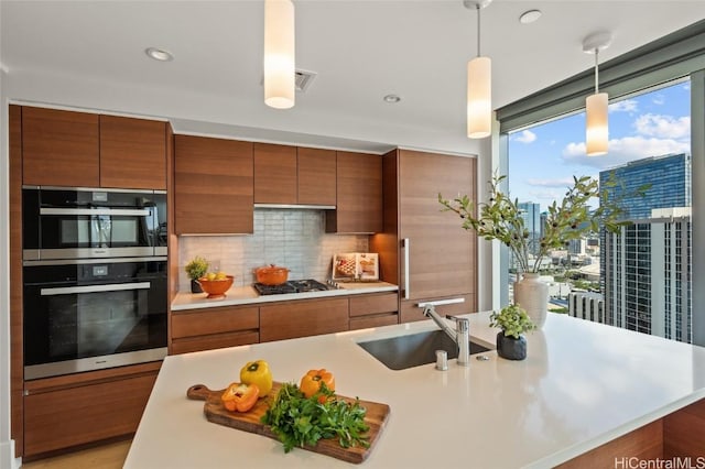 kitchen with a kitchen island with sink, sink, hanging light fixtures, decorative backsplash, and stainless steel appliances