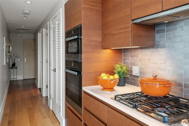 kitchen featuring light wood-type flooring, tasteful backsplash, and stainless steel gas stovetop