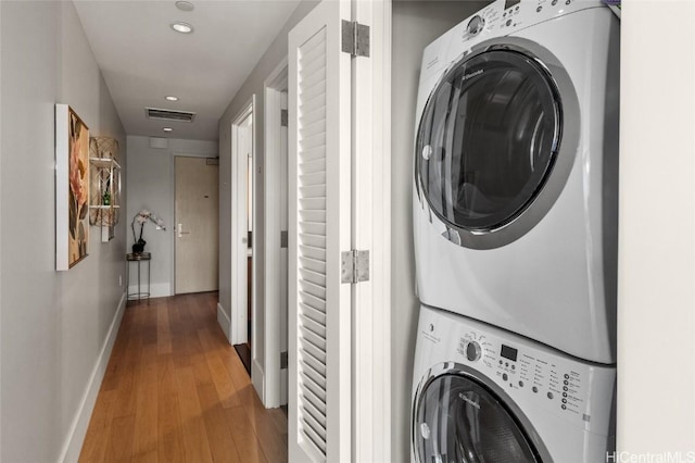 washroom with wood-type flooring and stacked washer and dryer