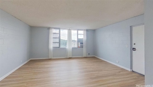 unfurnished room featuring light wood-type flooring and a textured ceiling