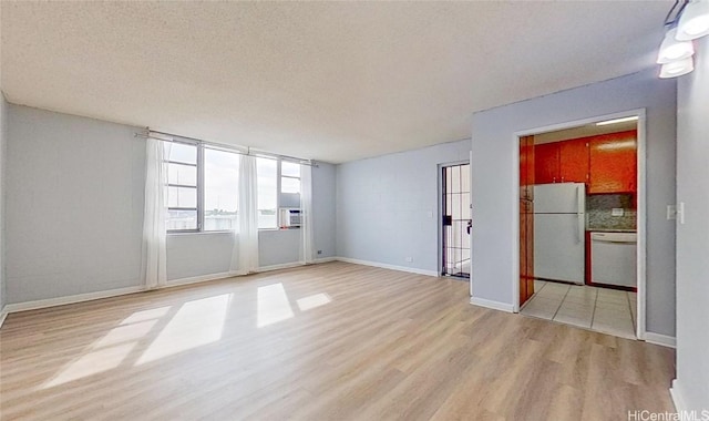 spare room with light hardwood / wood-style flooring, cooling unit, and a textured ceiling