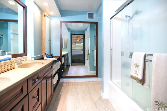 bathroom featuring hardwood / wood-style floors, vanity, ceiling fan, and combined bath / shower with glass door