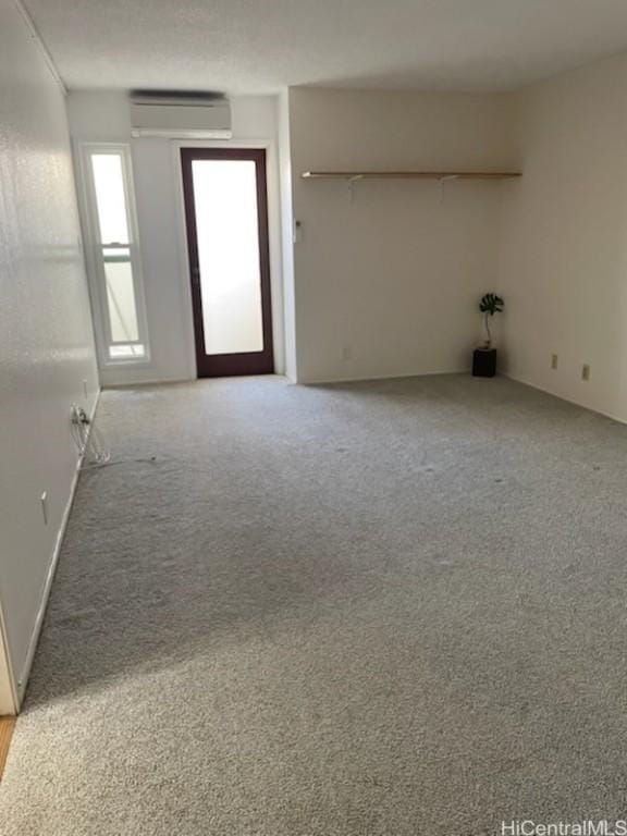 unfurnished room featuring light carpet and a wall mounted air conditioner