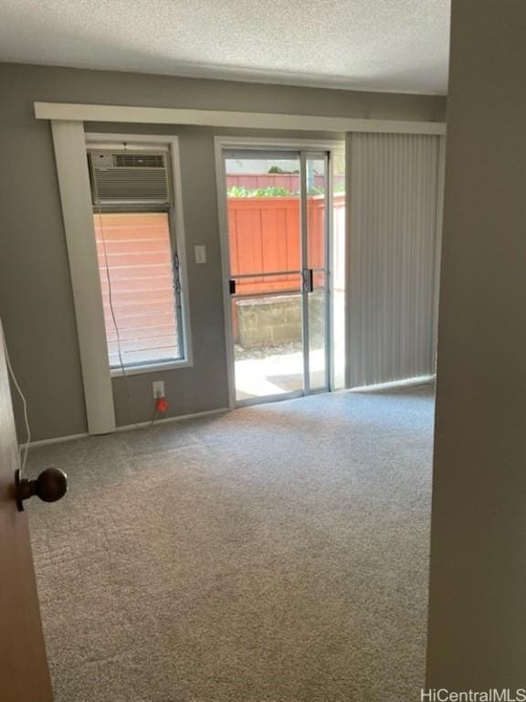 carpeted spare room with an AC wall unit and a textured ceiling