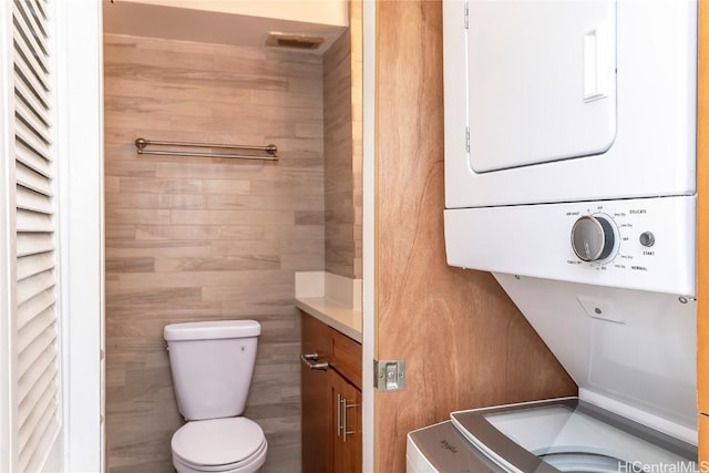 bathroom with stacked washing maching and dryer and toilet