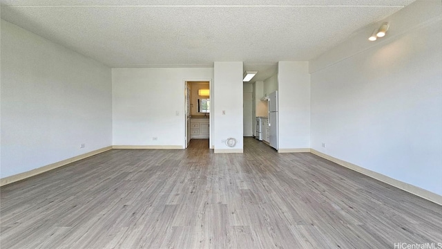 unfurnished living room featuring light wood-type flooring and a textured ceiling