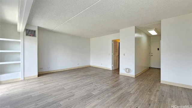 spare room featuring a textured ceiling and light hardwood / wood-style flooring