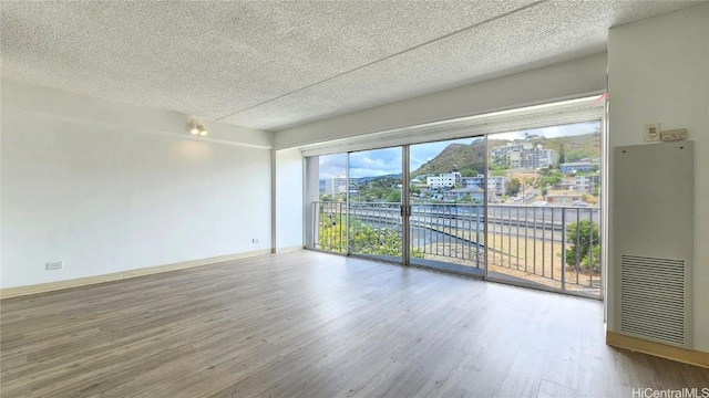 empty room with hardwood / wood-style flooring and a textured ceiling