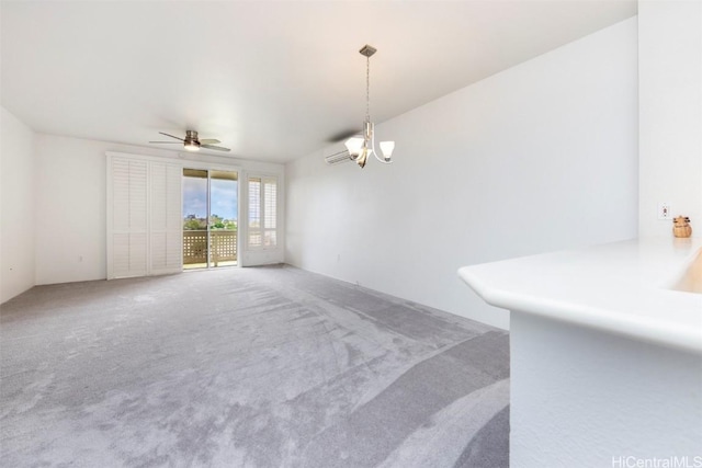 spare room with ceiling fan with notable chandelier and carpet floors