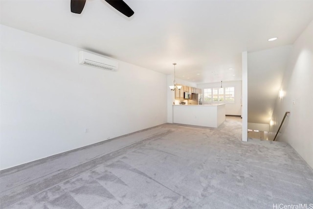 unfurnished living room featuring ceiling fan with notable chandelier, light carpet, and a wall unit AC