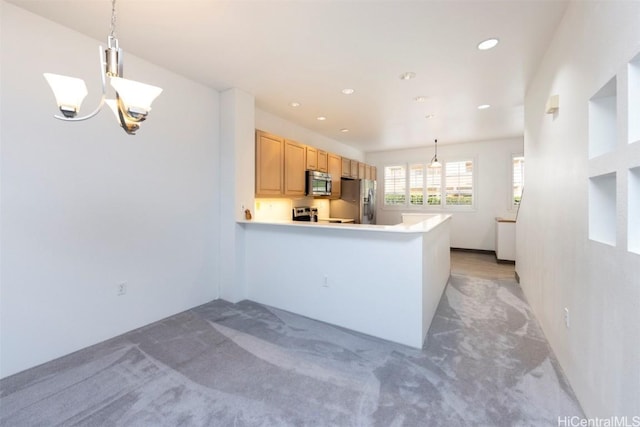 kitchen featuring kitchen peninsula, appliances with stainless steel finishes, light brown cabinets, and decorative light fixtures