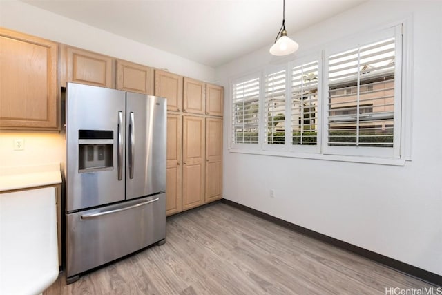 kitchen featuring stainless steel refrigerator with ice dispenser, light brown cabinets, light hardwood / wood-style floors, and pendant lighting