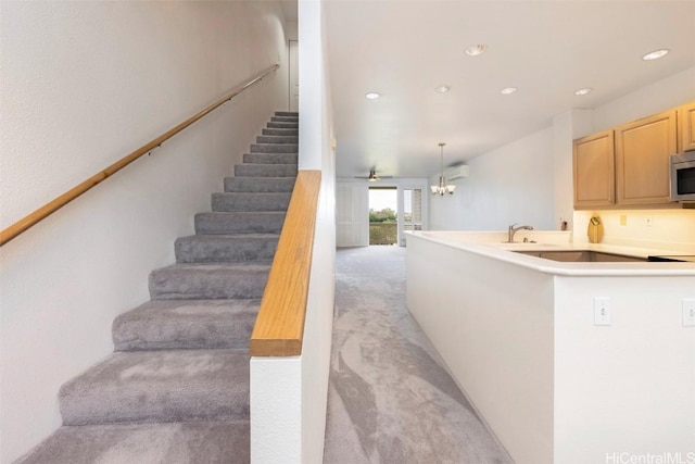 staircase with ceiling fan, sink, and carpet floors