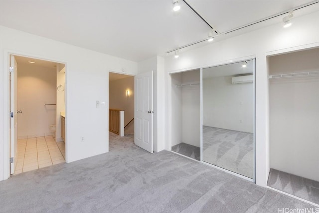 unfurnished bedroom featuring a wall unit AC, connected bathroom, and light carpet