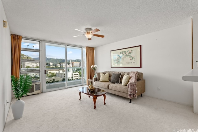 carpeted living room featuring a textured ceiling, expansive windows, and ceiling fan