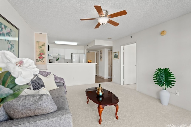 living room featuring a textured ceiling, light colored carpet, and ceiling fan