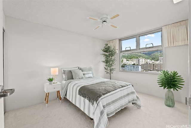 carpeted bedroom with ceiling fan and a textured ceiling