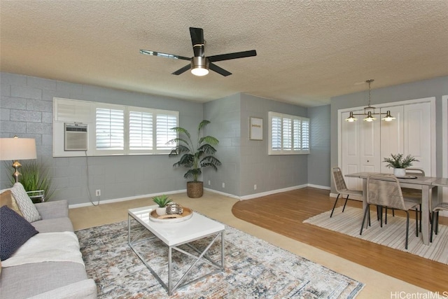 living room featuring ceiling fan with notable chandelier, a textured ceiling, and a wealth of natural light