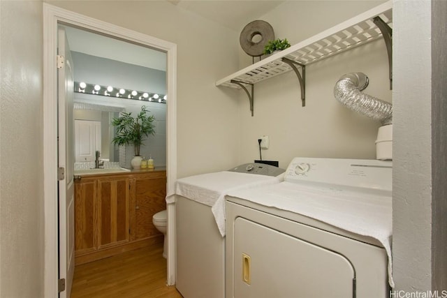 washroom with light wood-type flooring, washing machine and dryer, and sink