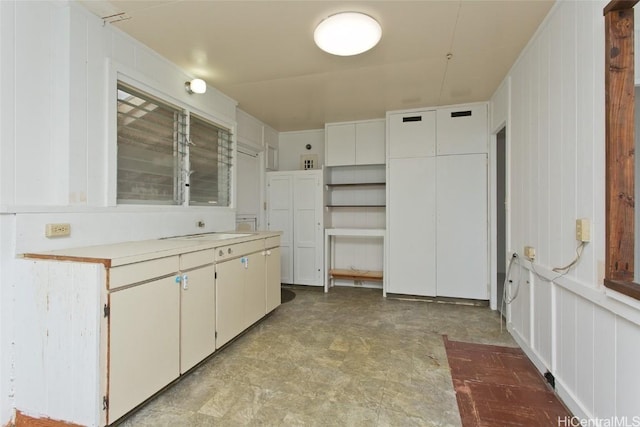 kitchen with sink, white cabinetry, and wood walls