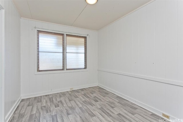 spare room featuring wooden walls and light wood-type flooring