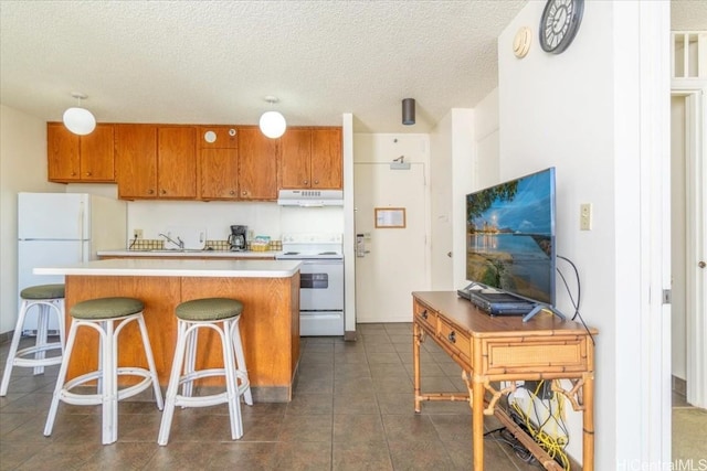 kitchen with a center island, white appliances, sink, a textured ceiling, and a breakfast bar area