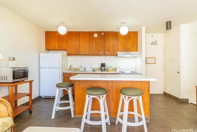 kitchen featuring a breakfast bar, a textured ceiling, white appliances, and a center island