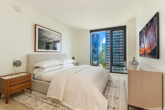 bedroom with access to exterior, floor to ceiling windows, and light hardwood / wood-style flooring