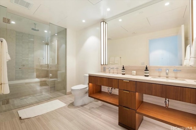 bathroom with toilet, vanity, decorative backsplash, hardwood / wood-style flooring, and a shower with shower door