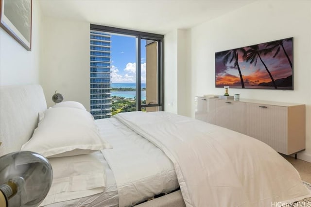 bedroom with a water view and expansive windows