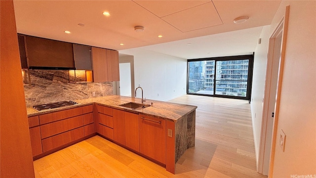 kitchen featuring a sink, light wood-style flooring, tasteful backsplash, and stainless steel gas stovetop