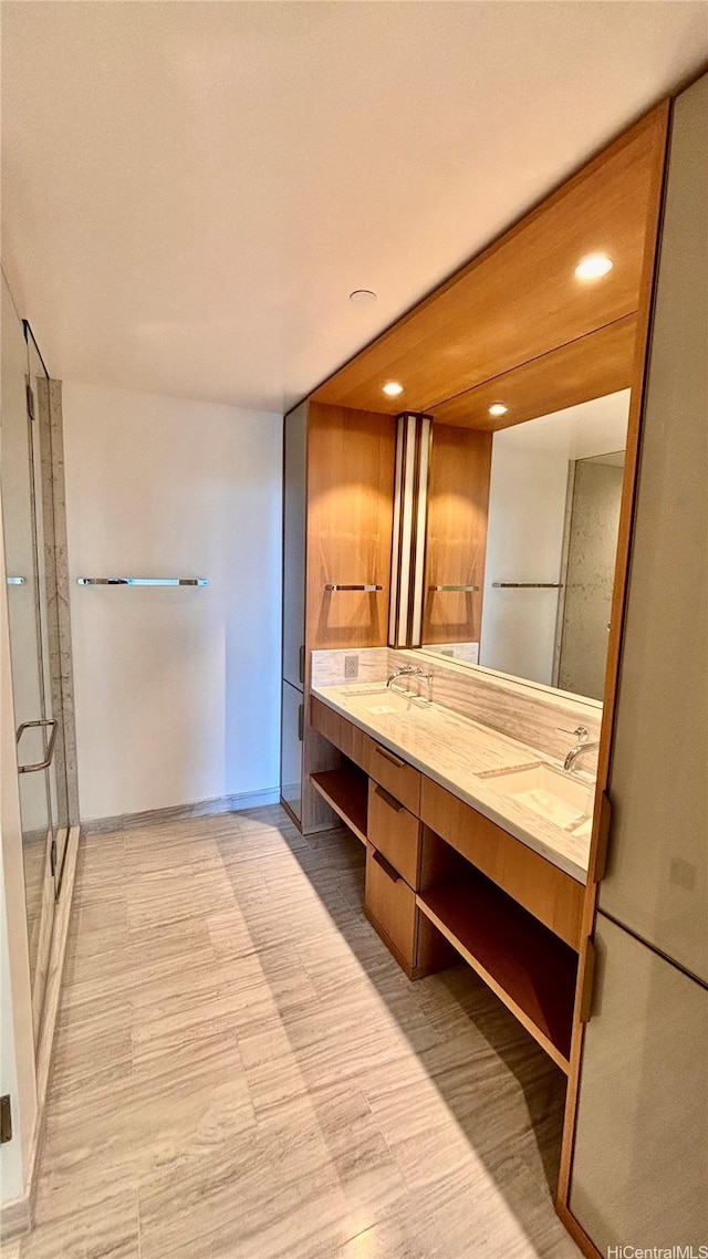 bathroom featuring double vanity, baseboards, recessed lighting, a sink, and a stall shower