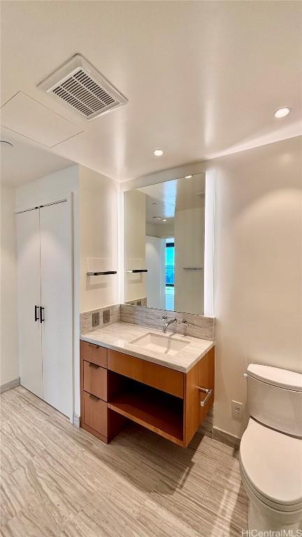 bathroom with hardwood / wood-style floors, vanity, and toilet