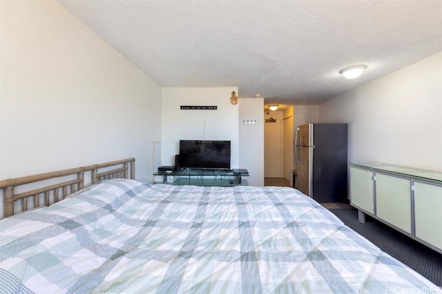 bedroom featuring dark colored carpet, a textured ceiling, and stainless steel refrigerator