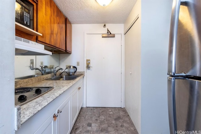 kitchen with a textured ceiling, extractor fan, electric stovetop, sink, and white cabinetry