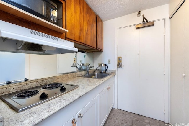 kitchen featuring white cabinets, stainless steel cooktop, sink, a textured ceiling, and light stone counters