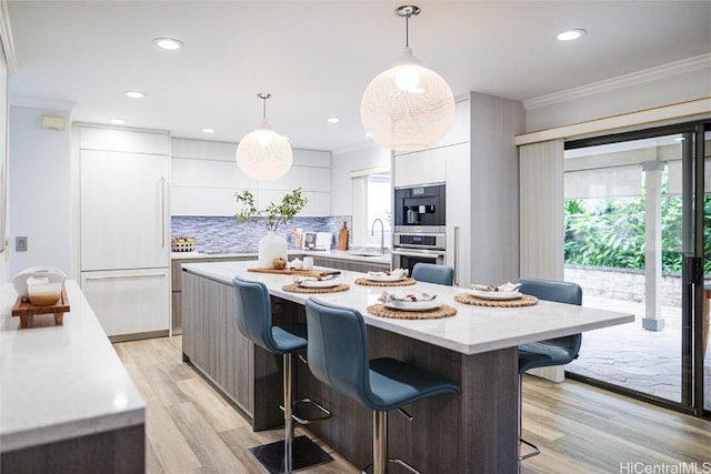 kitchen featuring white cabinetry, hanging light fixtures, backsplash, and paneled refrigerator